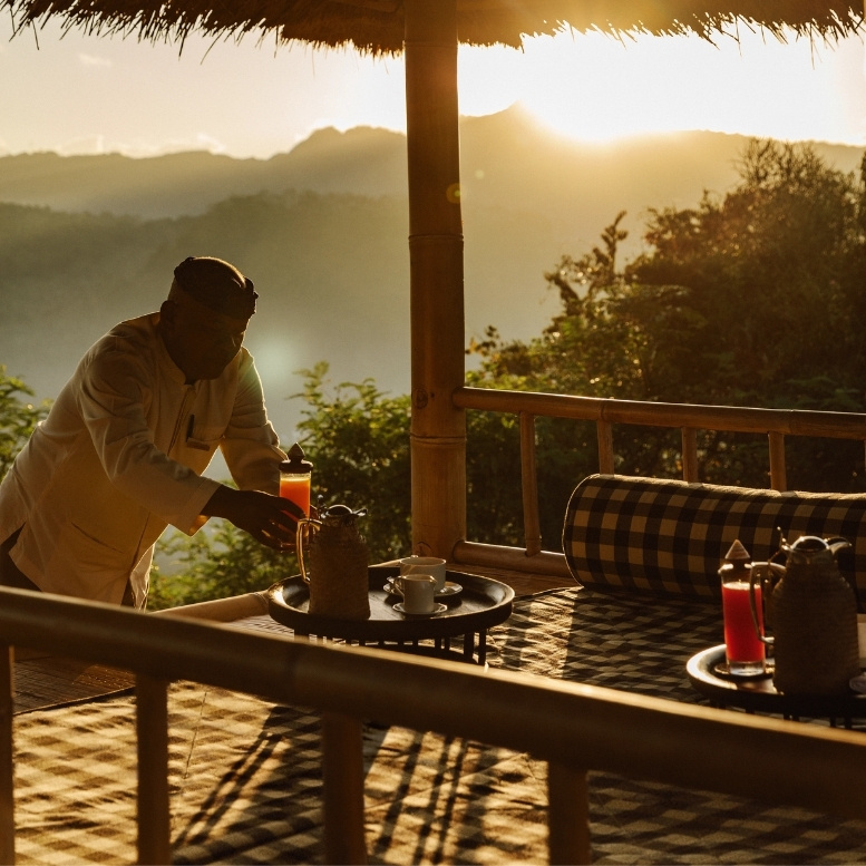 Petit-déjeuner servi sur la terrasse de l'Amankila à Bali avec vue sur les collines au lever du soleil.