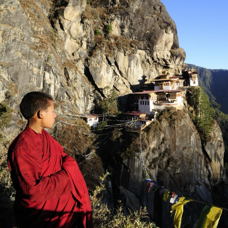 Jeune moine bouddhiste contemplant le monastère de Taktsang, le célèbre Nid du Tigre, au Bhoutan.
