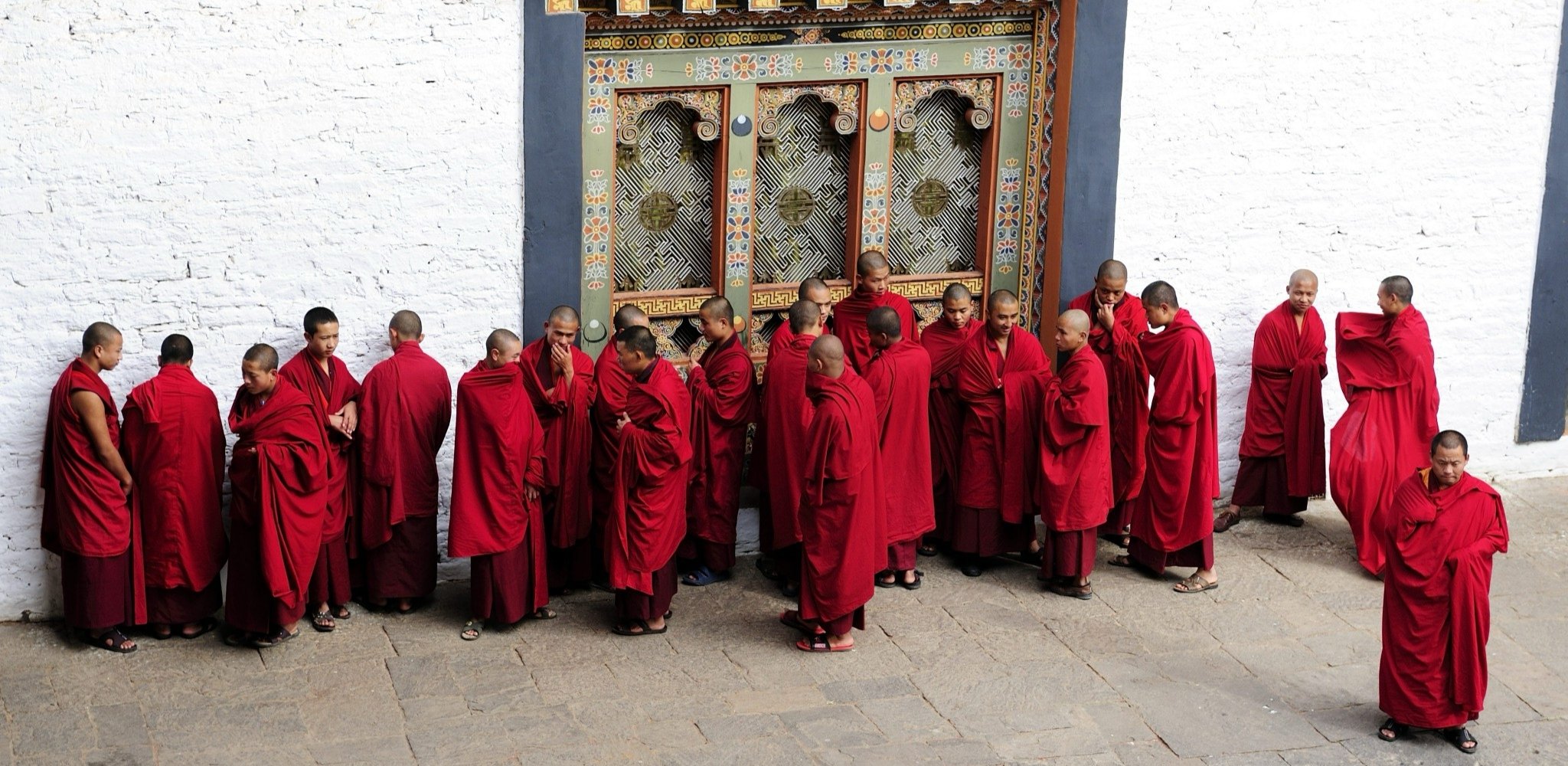 Jeunes moines bouddhistes rassemblés devant les portes du Punakha Dzong au Bhoutan. Voyage sur mesure au Bhoutan avec Horizons Nouveaux