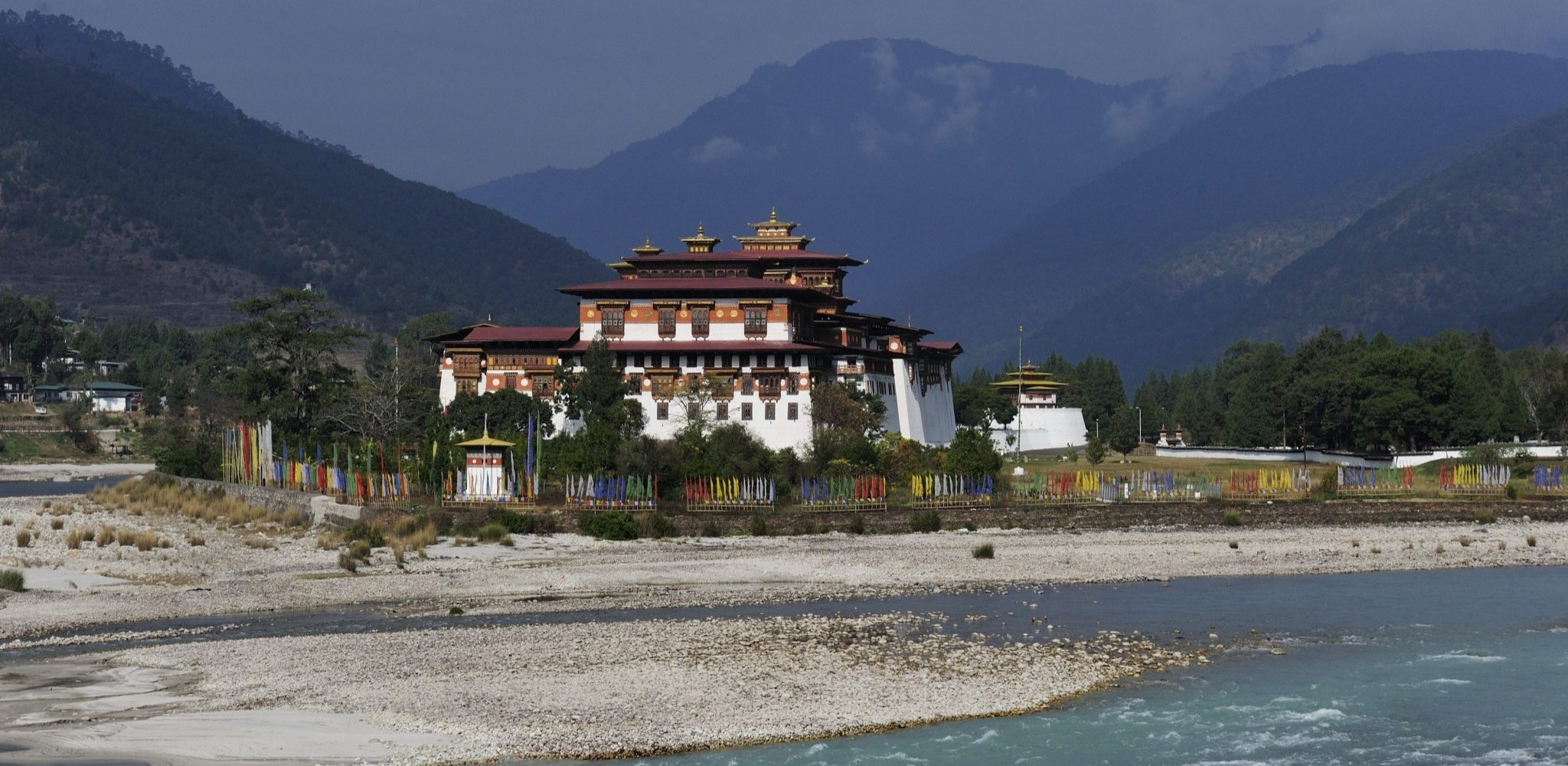 Vue du Punakha Dzong, forteresse-monastère emblématique du Bhoutan, au bord de la rivière Mo Chhu. A découvrir lors d'un voyage sur mesure au Bhoutan avec Horizons Nouveaux, agence de voyage suisse spécialiste du Bhoutan depuis plus de 30 ans