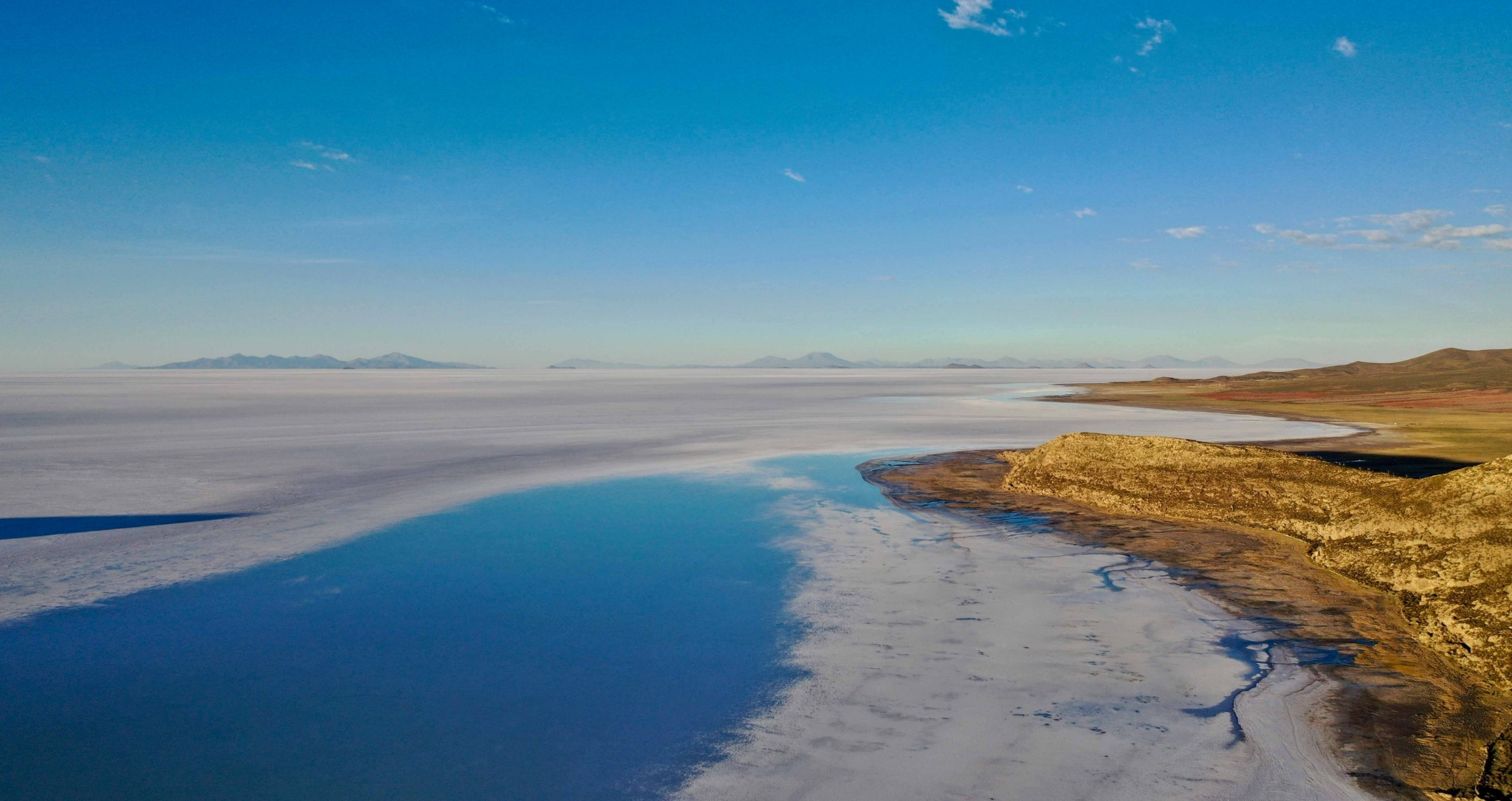 Vue aérienne des rives du Salar d'Uyuni, où les eaux saisonnières rencontrent l'immensité du plus grand désert de sel au monde, en Bolivie. A découvrir lors d'un voyage sur mesure en Bolivie avec Horizons Nouveaux.