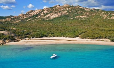 Vue aérienne d’une plage de sable blanc et d’un bateau dans les eaux cristallines du sud de la Sardaigne.