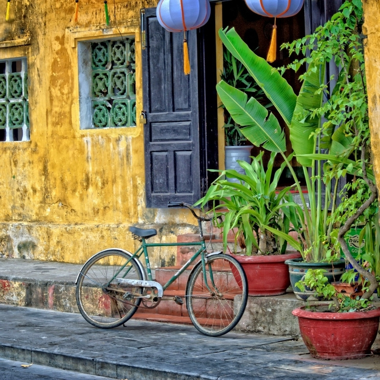 Vélo traditionnel devant une maison ancienne de Hội An au Vietnam, entre lanternes colorées, architecture préservée, atmosphère authentique et voyage sur mesure à la découverte du Vietnam