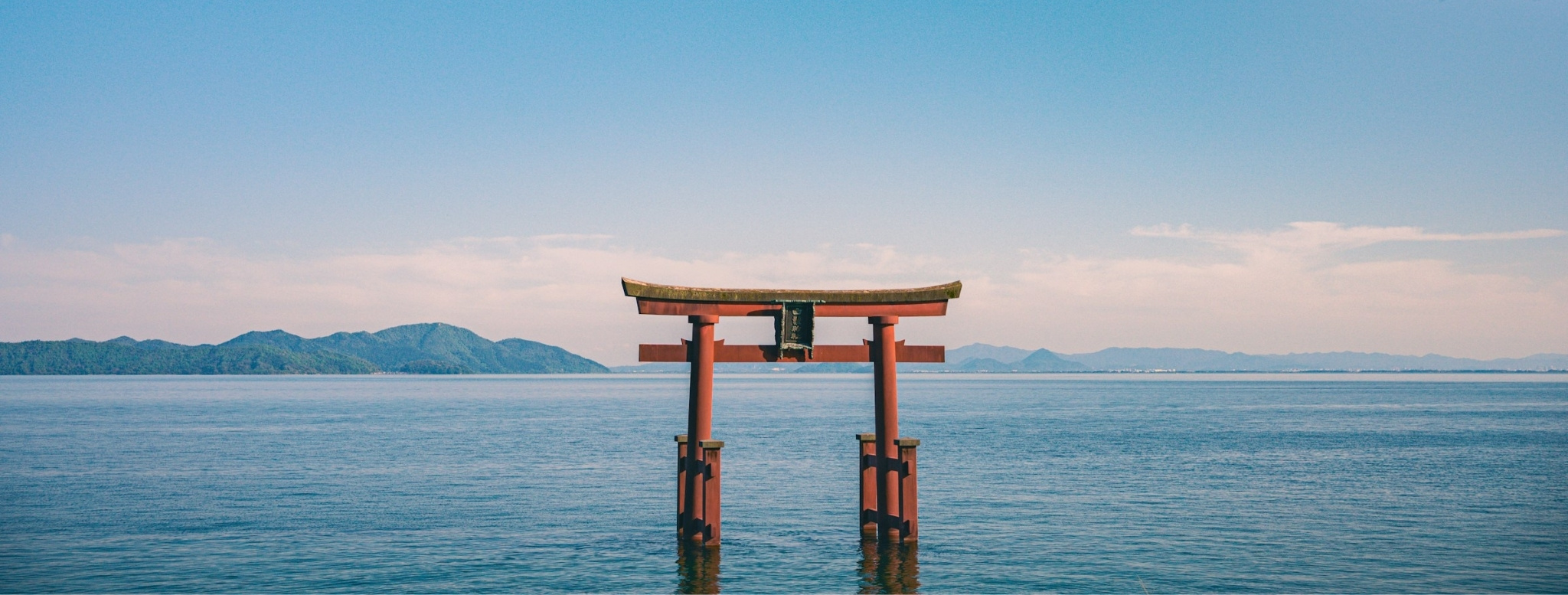 Torii rouge se dressant au cœur des eaux calmes du Japon, symbole spirituel reliant la nature, la mer et les traditions ancestrales de l’archipel – Horizons Nouveaux