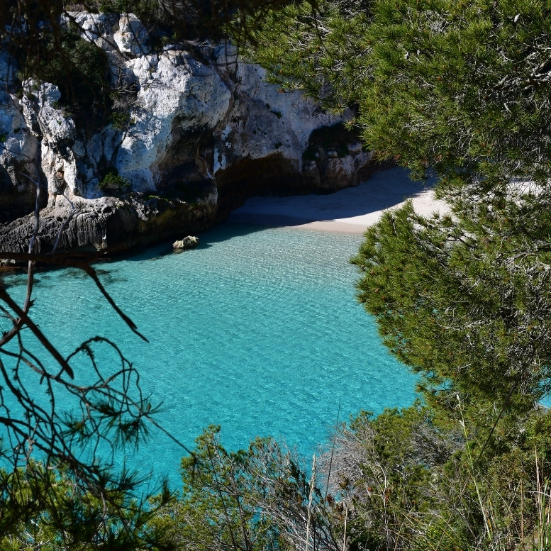 Crique aux eaux turquoise bordée de falaises calcaires sur la côte de Minorque aux Baléares.