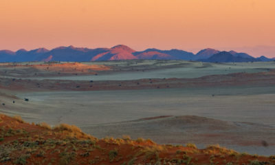 Panorama du désert de Namibie au crépuscule, dunes, montagnes et espaces infinis du Namib, destination emblématique d’un voyage sur mesure en Namibie.