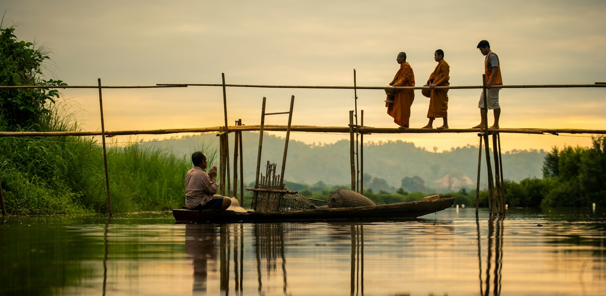 Moines bouddhistes traversant un pont en bambou au nord de la Thaïlande, scène authentique entre spiritualité, traditions locales, rencontres culturelles et voyage sur mesure en Thaïlande.