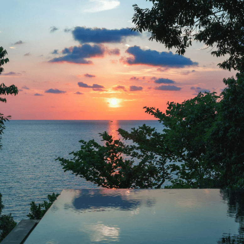 Coucher de soleil sur la mer, contemplé depuis une piscine à débordement entourée de végétation tropicale. Hotel à découvrir lors d'un voyage au Cambodge avec Horizons Nouveaux