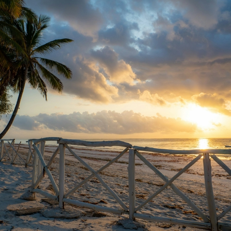 Plage de Diani Beach au Kenya au coucher du soleil, entre océan Indien, sable blanc bordé de palmiers et séjour balnéaire haut de gamme après un safari sur mesure au Kenya.