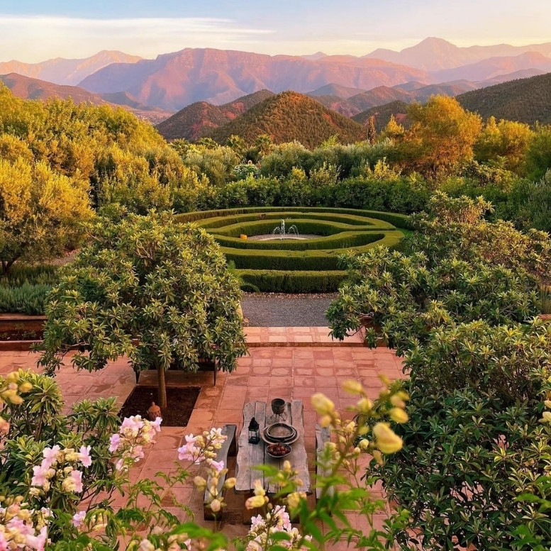 Jardin de la Kasbah Bab Ourika avec vue panoramique sur les montagnes de l'Atlas au coucher du soleil.