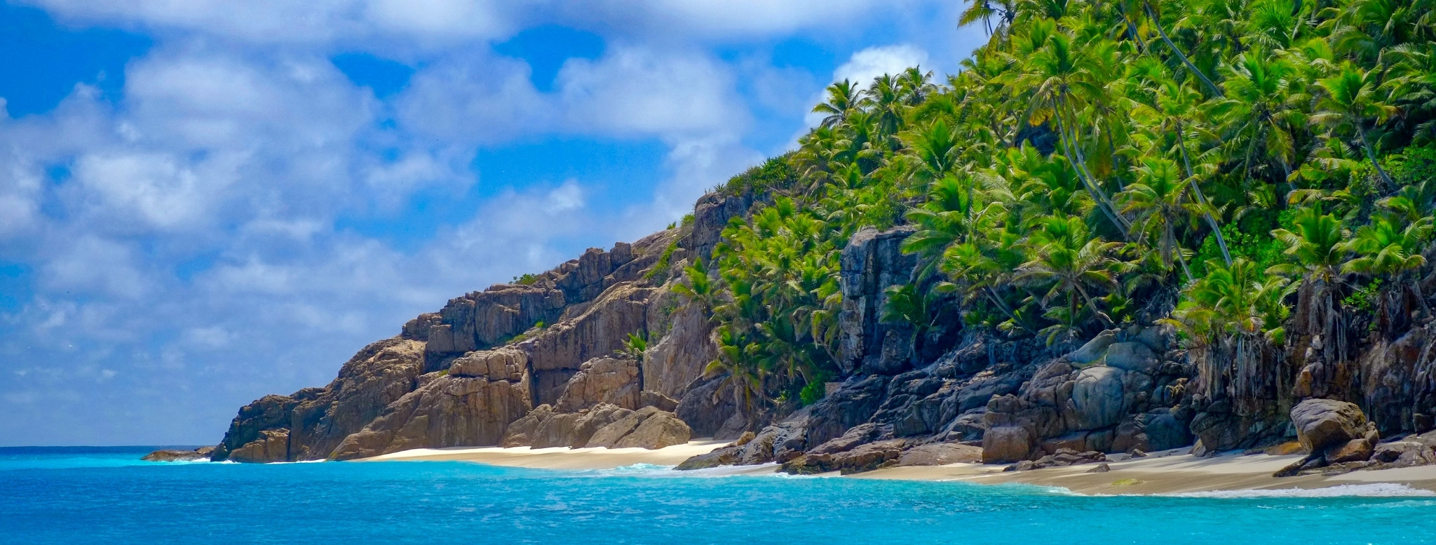 Plage sauvage bordée de blocs de granit et de cocotiers sur une île des Seychelles, où les eaux turquoise de l’océan Indien rencontrent l’une des plus belles natures tropicales au monde – Horizons Nouveaux