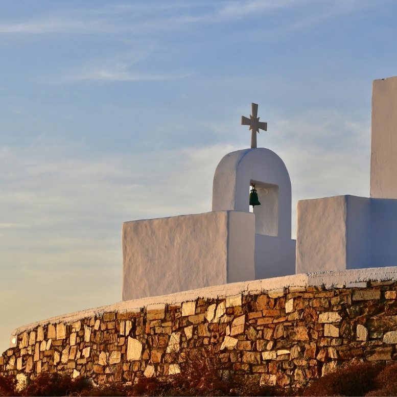 Petite chapelle blanche dominant les collines d’Antiparos, baignée par la lumière dorée de la fin du jour – un voyage sur mesure en Grèce à la découverte des Cyclades les plus confidentielles, entre villages paisibles, criques secrètes et douceur méditerranéenne – Horizons Nouveaux.