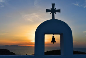 Chapelle blanche avec cloche en silhouette au coucher du soleil à Antiparos dans les Cyclades