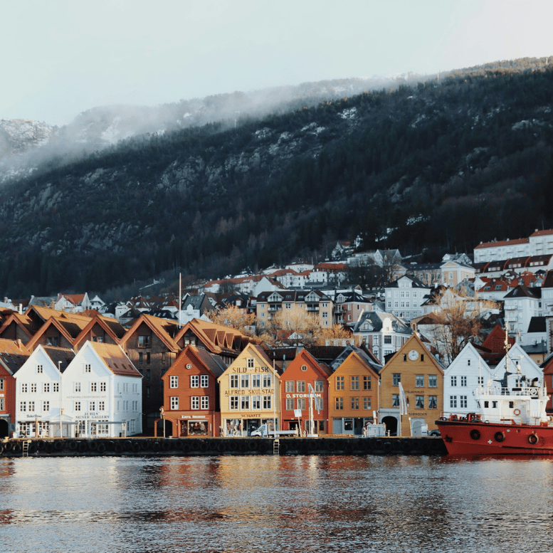 Façades colorées du quartier historique de Bryggen à Bergen, le long du port, avec les montagnes en arrière-plan.
