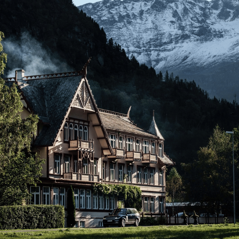 Hôtel traditionnel norvégien à l’architecture en bois, niché au pied de montagnes enneigées et entouré de forêts.