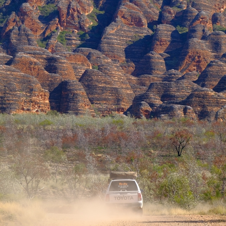 Véhicule tout-terrain traversant les paysages sauvages des Bungle Bungle Range dans le parc national de Purnululu, en Australie-Occidentale, au pied des célèbres formations rocheuses striées classées au patrimoine mondial de l'UNESCO.