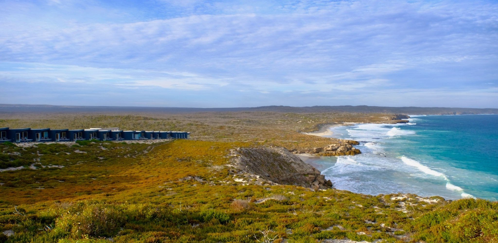 Littoral sauvage d'Australie-Méridionale bordé de falaises et de plages de sable blanc, avec un lodge surplombant les eaux turquoise de l'océan Austral au cœur d'un environnement naturel préservé.