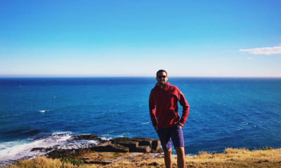 Jonas, managing director d’Horizons Nouveaux, face à l’océan sur une côte sauvage en Nouvelle-Zélande – reconnaissance terrain et exploration sur mesure