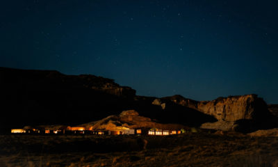 Vue nocturne d'Amangiri, dans le désert de l'Utah, où les bâtiments discrètement éclairés se fondent au pied de falaises de grès sous un ciel étoilé d'une remarquable pureté.