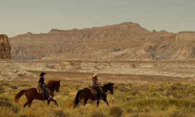 Cavaliers explorant les vastes paysages désertiques du sud-ouest américain près d'Amangiri, avec des chevaux traversant une plaine aride dominée par d'imposantes mesas et falaises de roche ocre.