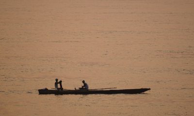 Deux personnes sur une pirogue pêchent au crépuscule sur le Fleuve Congo.