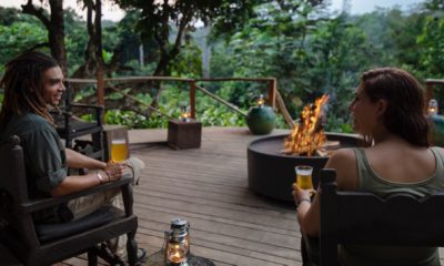 Un guide de safari et une touriste prennent l'apéritif autour du feu de camp sur la terrasse d'observation entourée de la forêt tropicale à Ngaga Lodge au Congo.