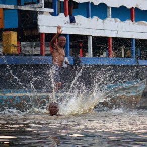 Enfants jouant dans l'eau près d'un grand bateau sur le fleuve Congo.
